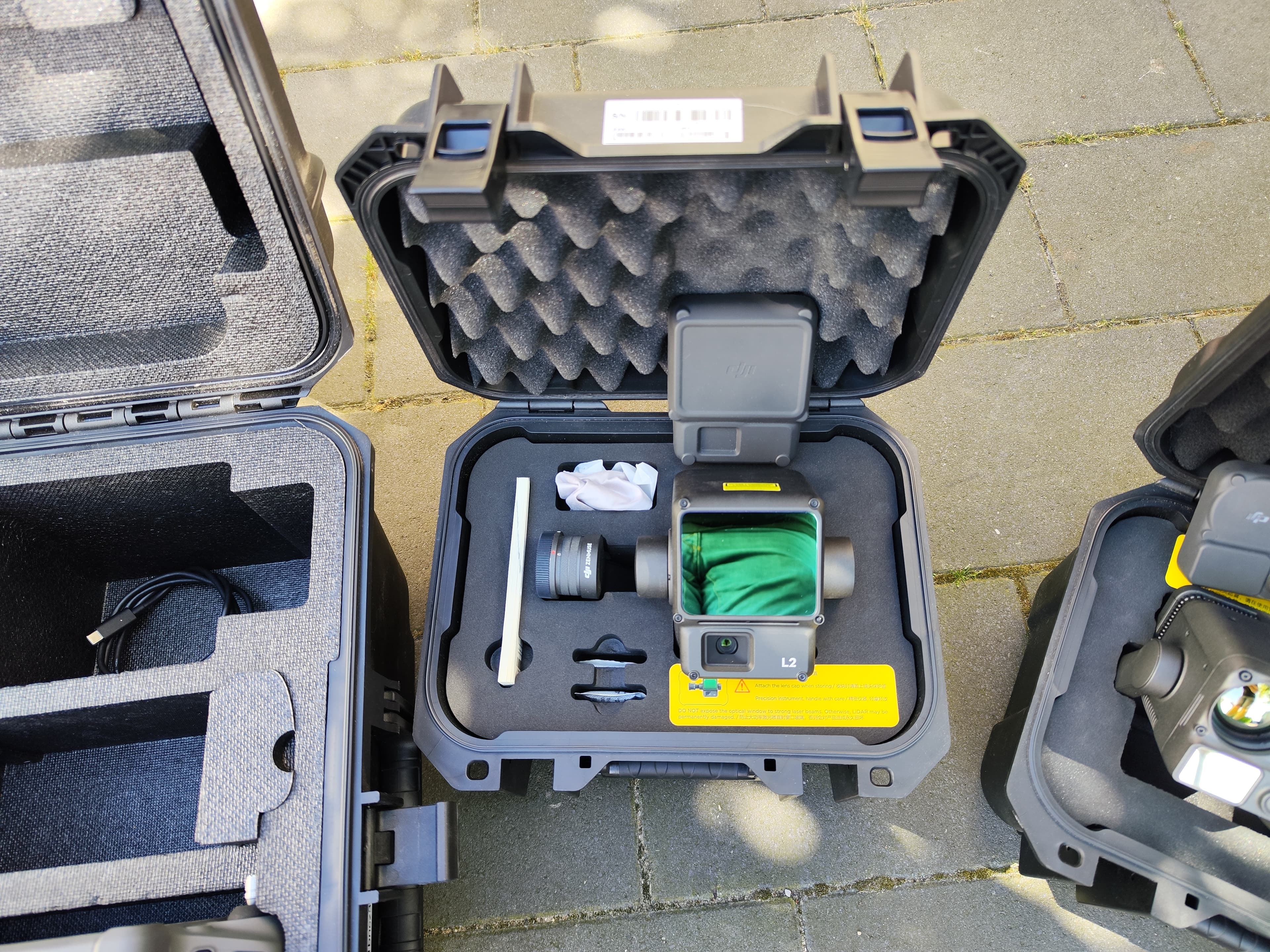 DJI Zenmuse L2 LiDAR-Sensor in einem offenen, schaumstoffgepolsterten schwarzen Hartschalenkoffer auf grauem Steinboden.